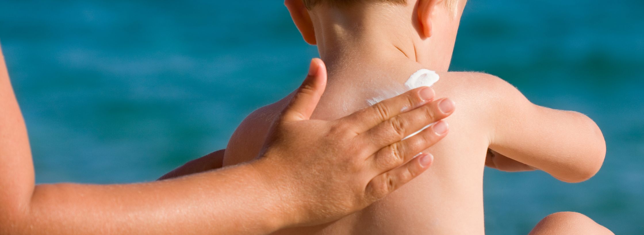 hand applying sunscreen to a small child's back